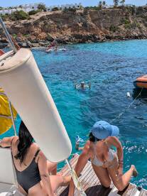 A lively scene featuring friends enjoying a sunny day on the water, with one person swimming and others preparing to join in — perfect for a fun-filled boating adventure.