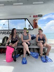 Three friends share a joyful moment aboard a boat, ready for snorkeling adventure in crystal-clear waters. Perfect for group outings and aquatic exploration.
