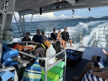 A lively group enjoys their time aboard a boat, ready for snorkeling adventures with drinks in hand, showcasing the perfect blend of relaxation and excitement on the water.