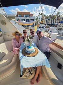 A cheerful group celebrates aboard a boat with a beautifully decorated cake, perfect for memorable gatherings and special occasions on the water.