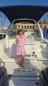 A joyful woman poses on the deck of a yacht named 'Sweetie Pie,' capturing the essence of a fun day on the water in Cabo San Lucas.