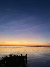 A stunning sunset over calm waters, with a dock silhouetted against the vibrant sky — perfect for capturing the beauty of nature.